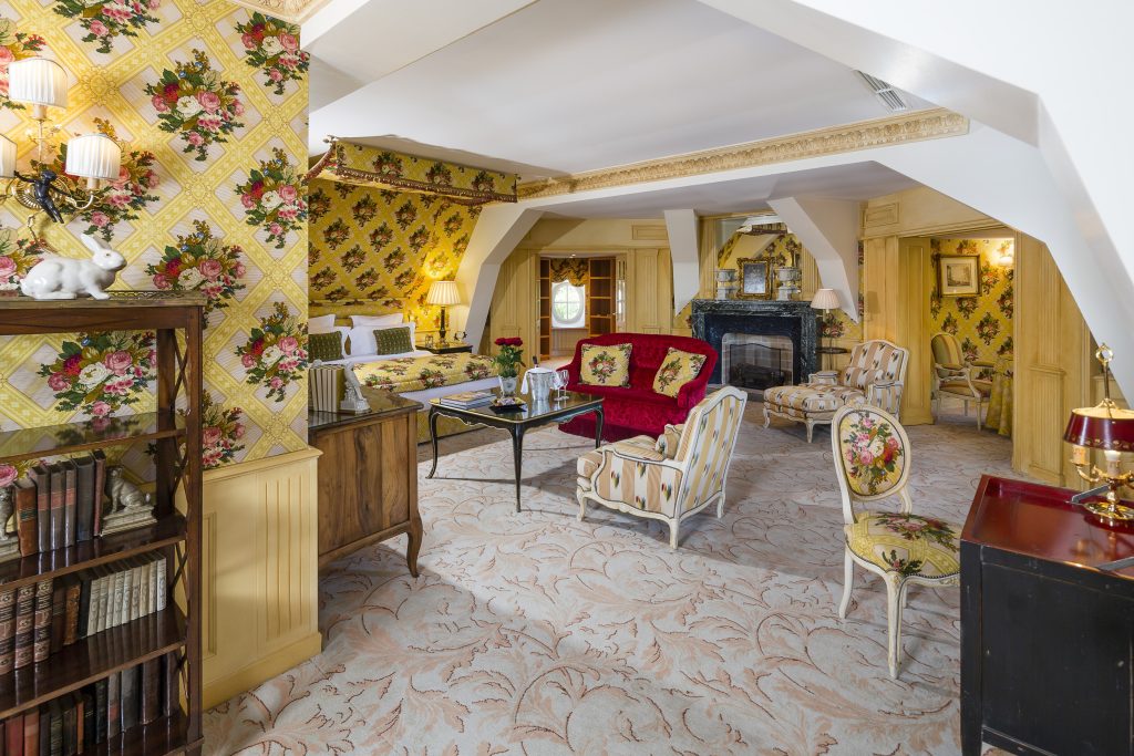 The Grand Suite sitting area with yellow floral walls and a fireplace