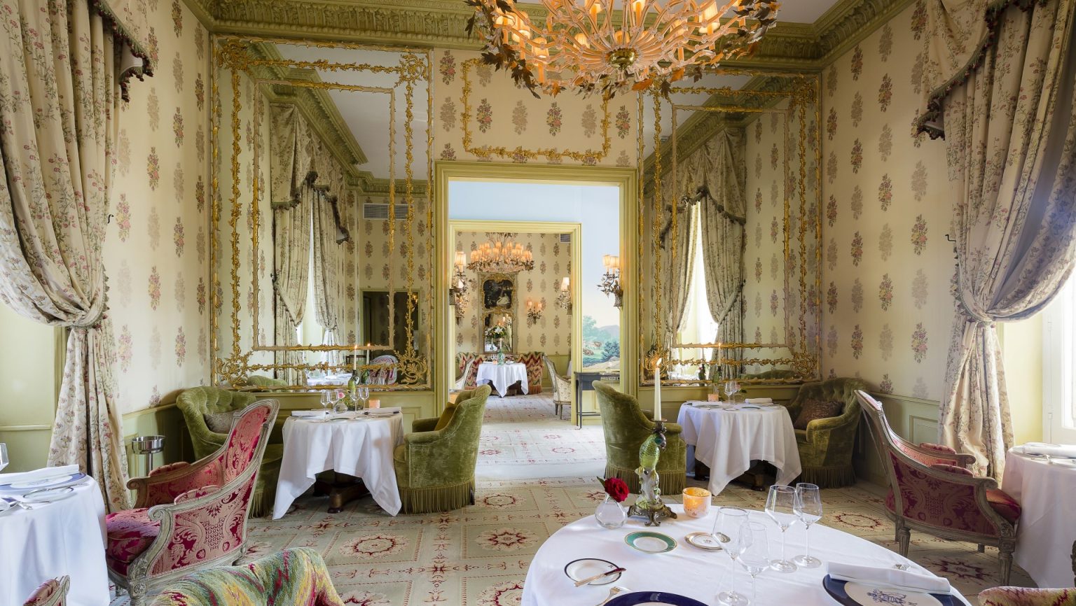 The Dining Room laid with round tables beneath chandeliers