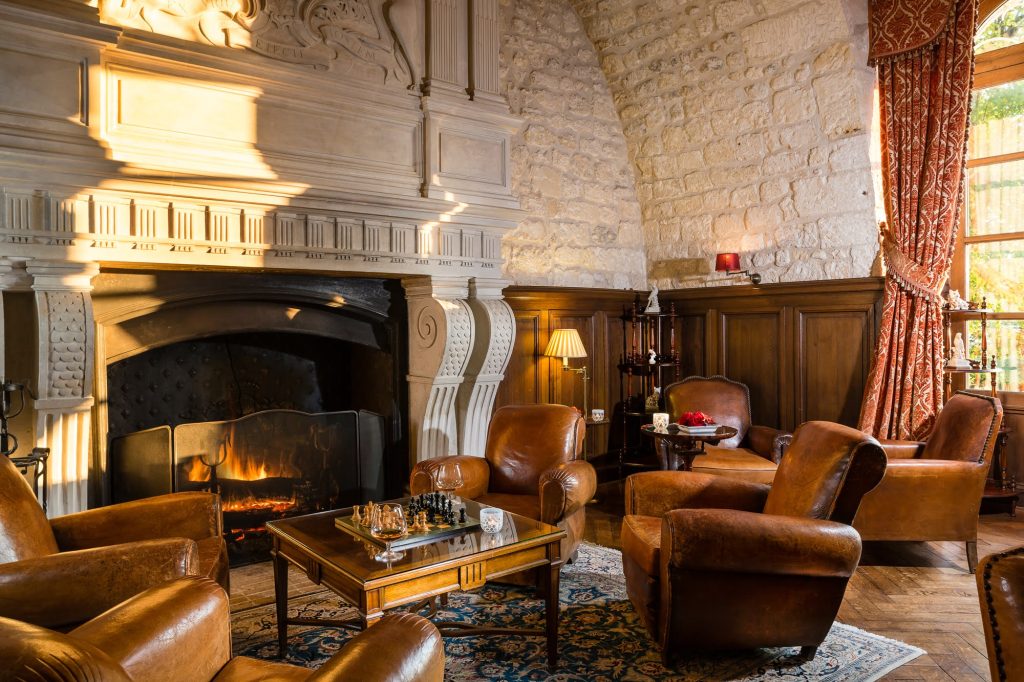 Leather armchairs around a stone fireplace in a salon
