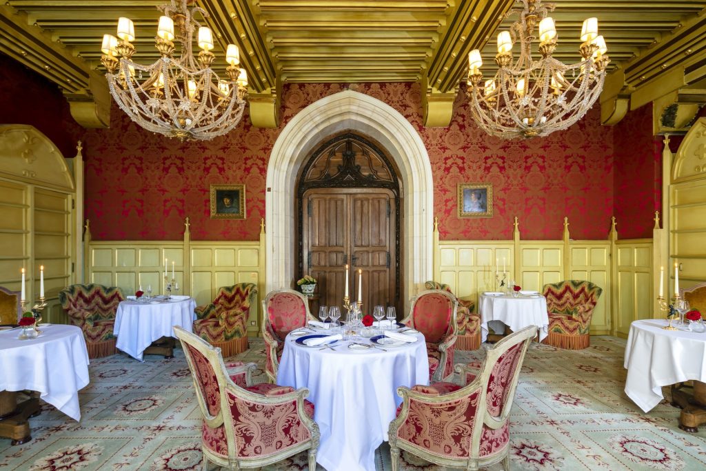 A dining salon with chandeliers and round tables laid for a meal