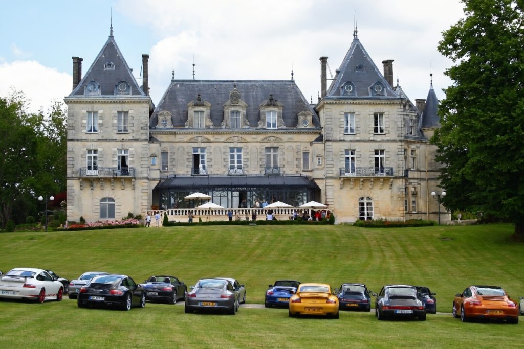 A line of cars on the lawn in front of the château