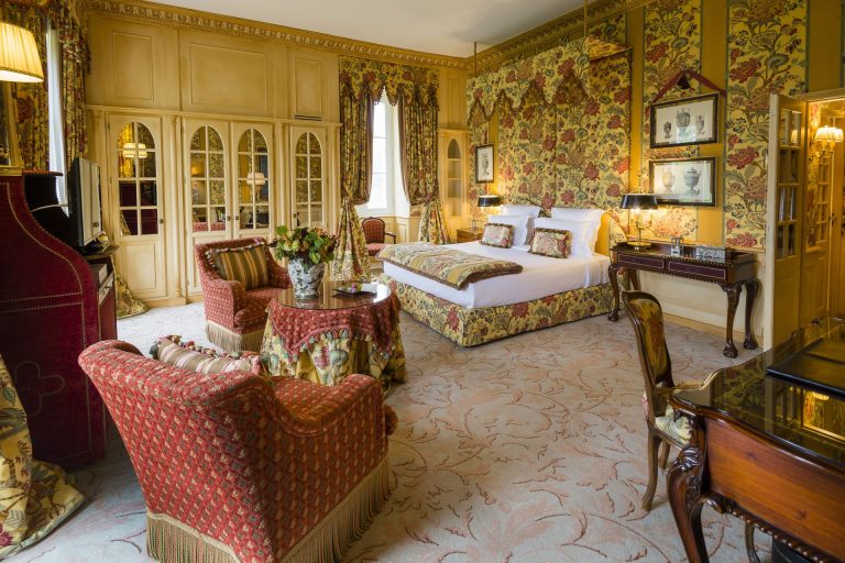 A Château Suite with a canopy bed, floral fabrics and armchairs