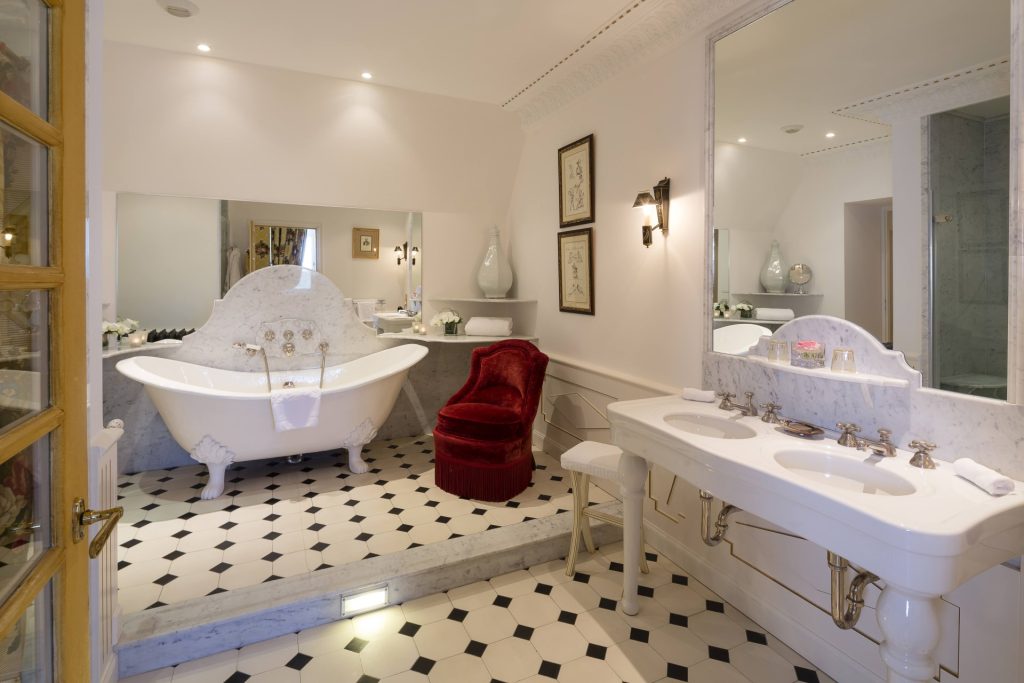 La salle de bains de la Grande Suite avec une baignoire libre-télescopique et un fauteuil rouge