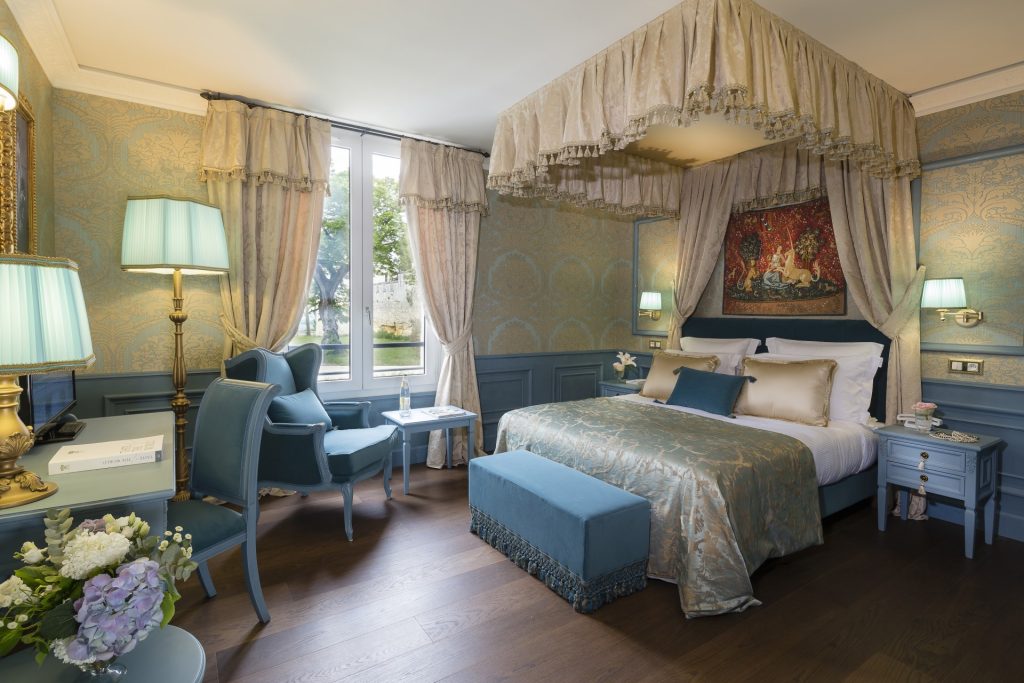 A Superior Room with a canopy bed and blue armchairs