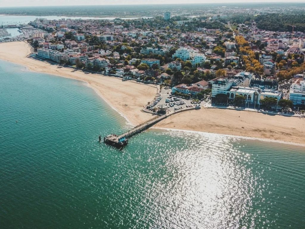 Aerial view of a seaside town with a sandy beach and a pier