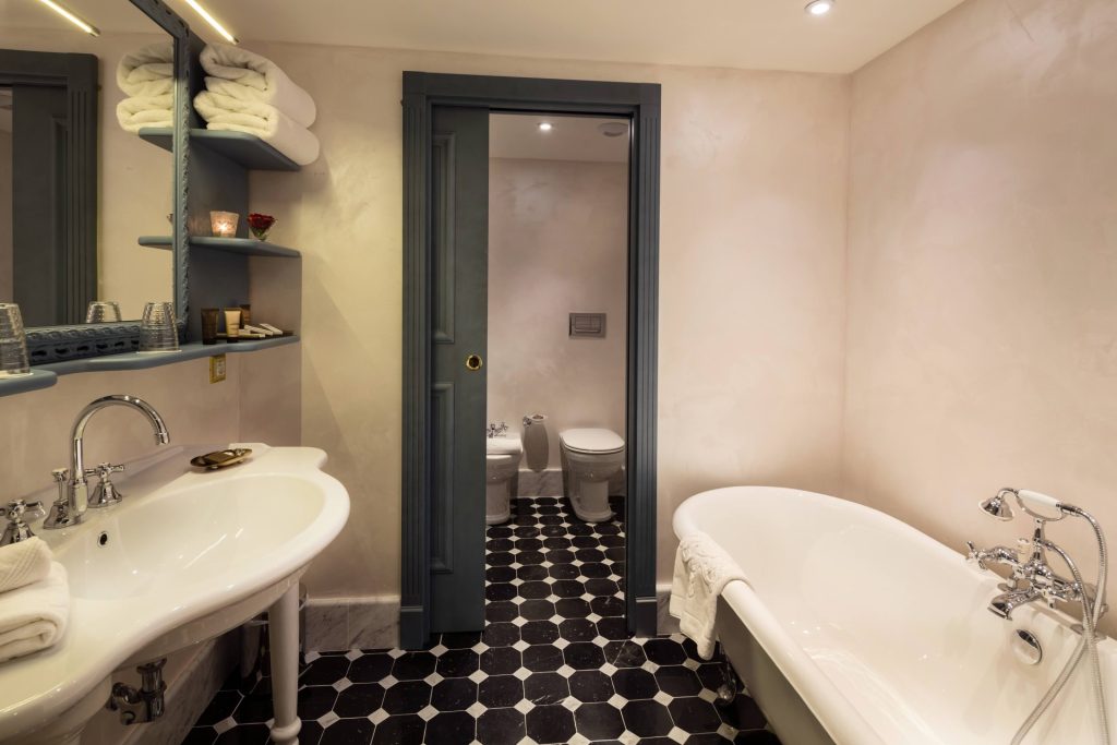A bathroom with a free-standing bathtub and a chequered floor