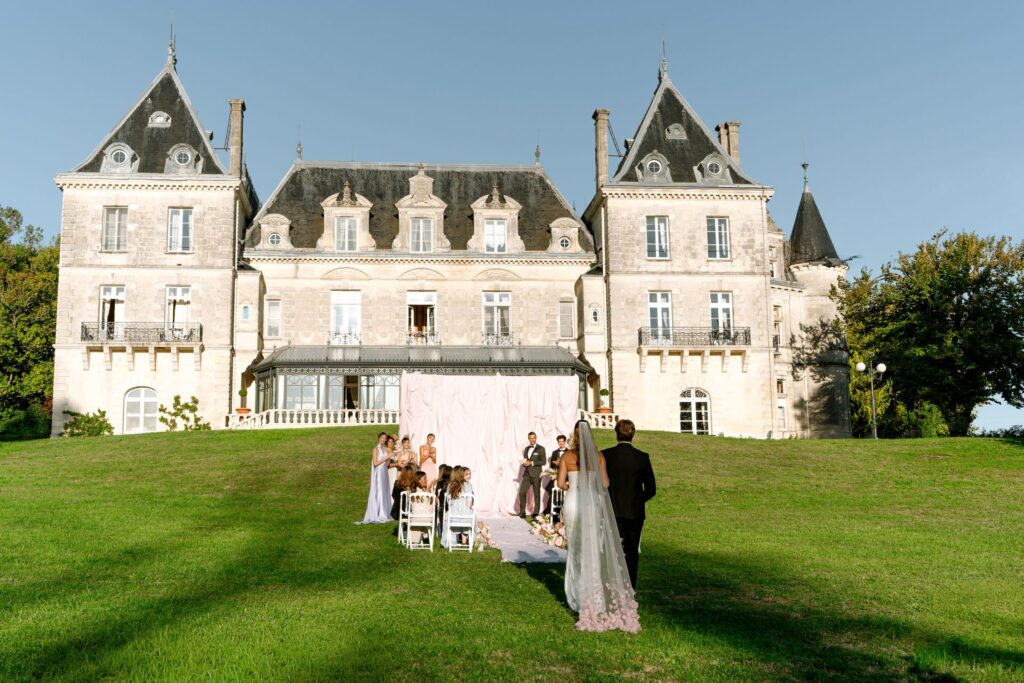 A pink-toned wedding scene in the light-filled corridors of Château de Mirambeau