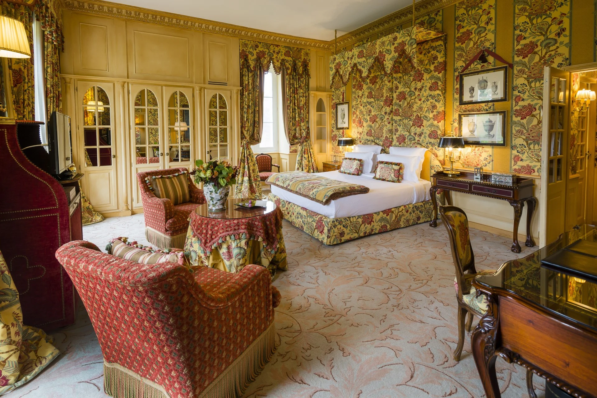 Une suite Château avec un lit à baldaquin, des tissus floraux et des fauteuils