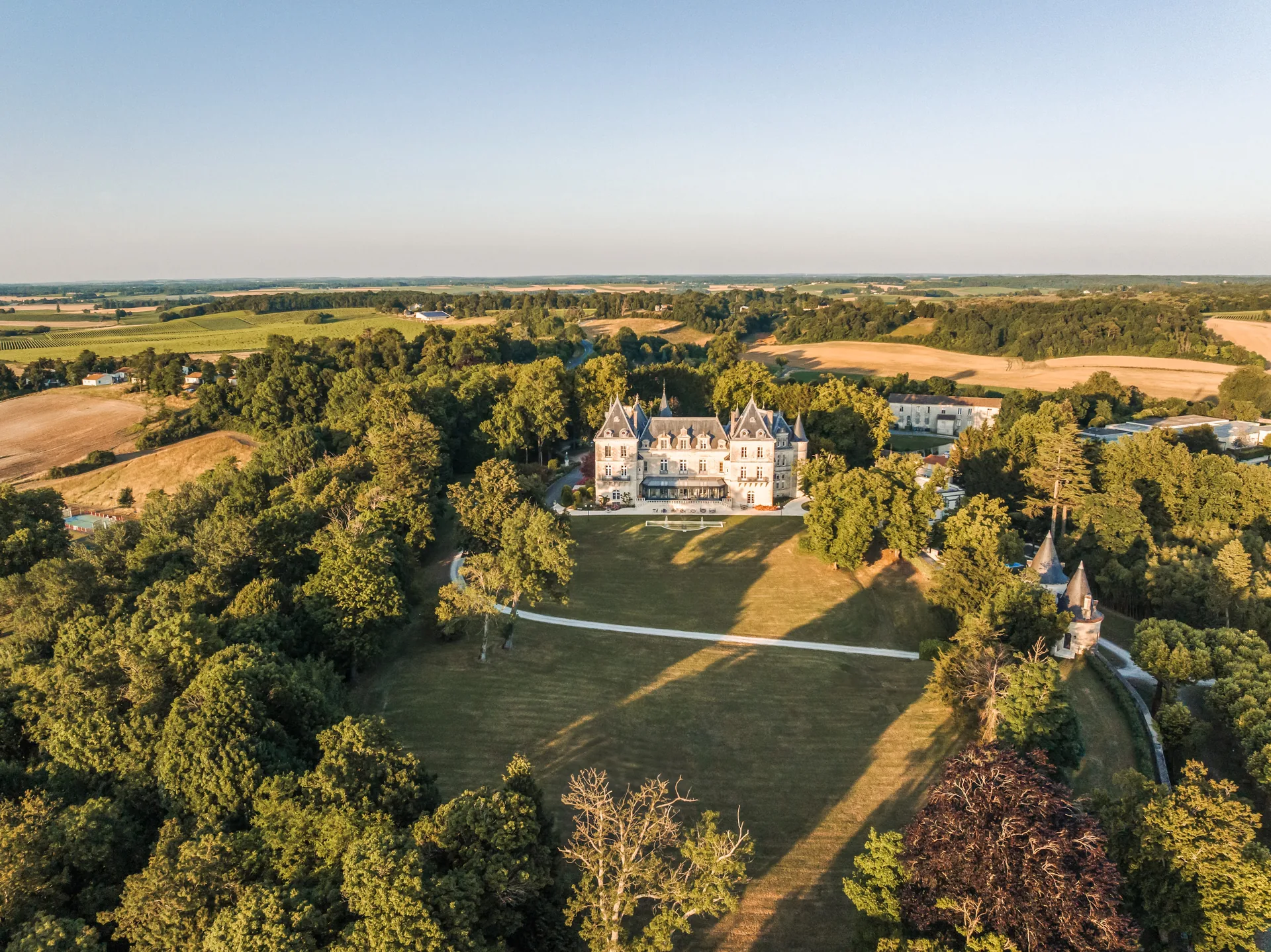 Aerial view of the château in its wooded park with lawns and the surrounding countryside