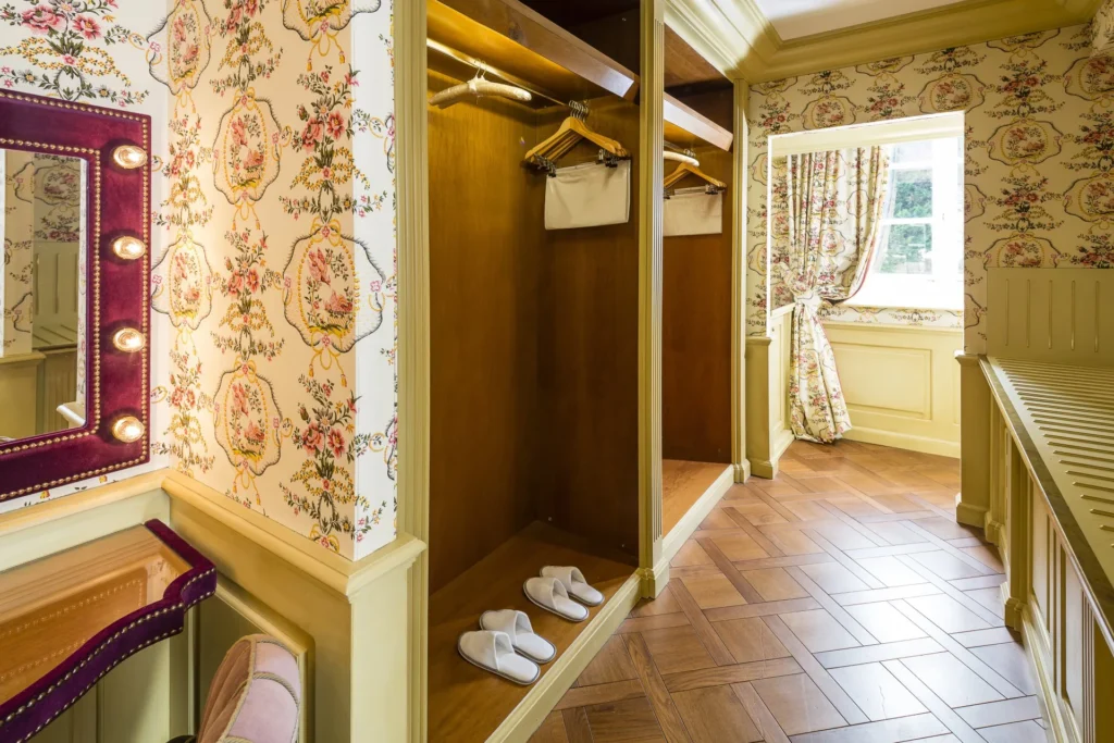 La zone de dressing d’une Galerie Suite avec des tissus murales floraux, un miroir de maquillage et une vue sur la chambre à coucher