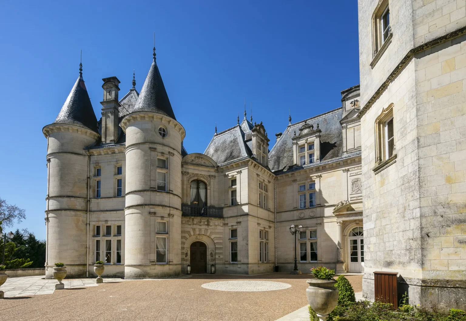 Les tours pointues et la façade en pierre du château sous un ciel bleu clair
