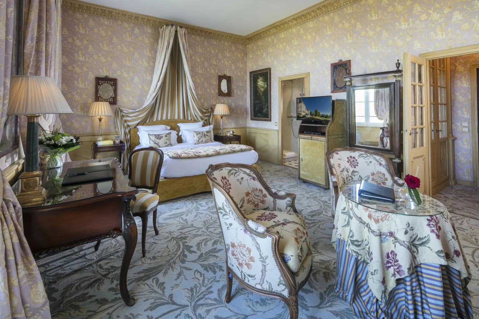A second-floor Junior Suite with a canopied bed, a writing desk and armchairs