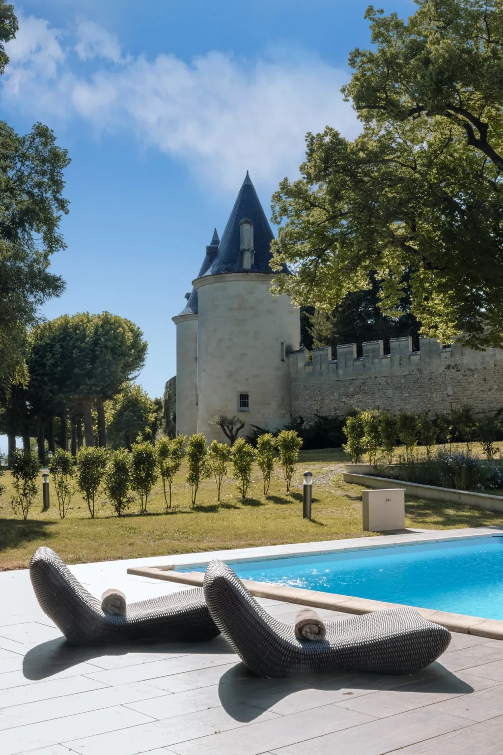Two loungers beside the pool beneath the château round tower and ramparts