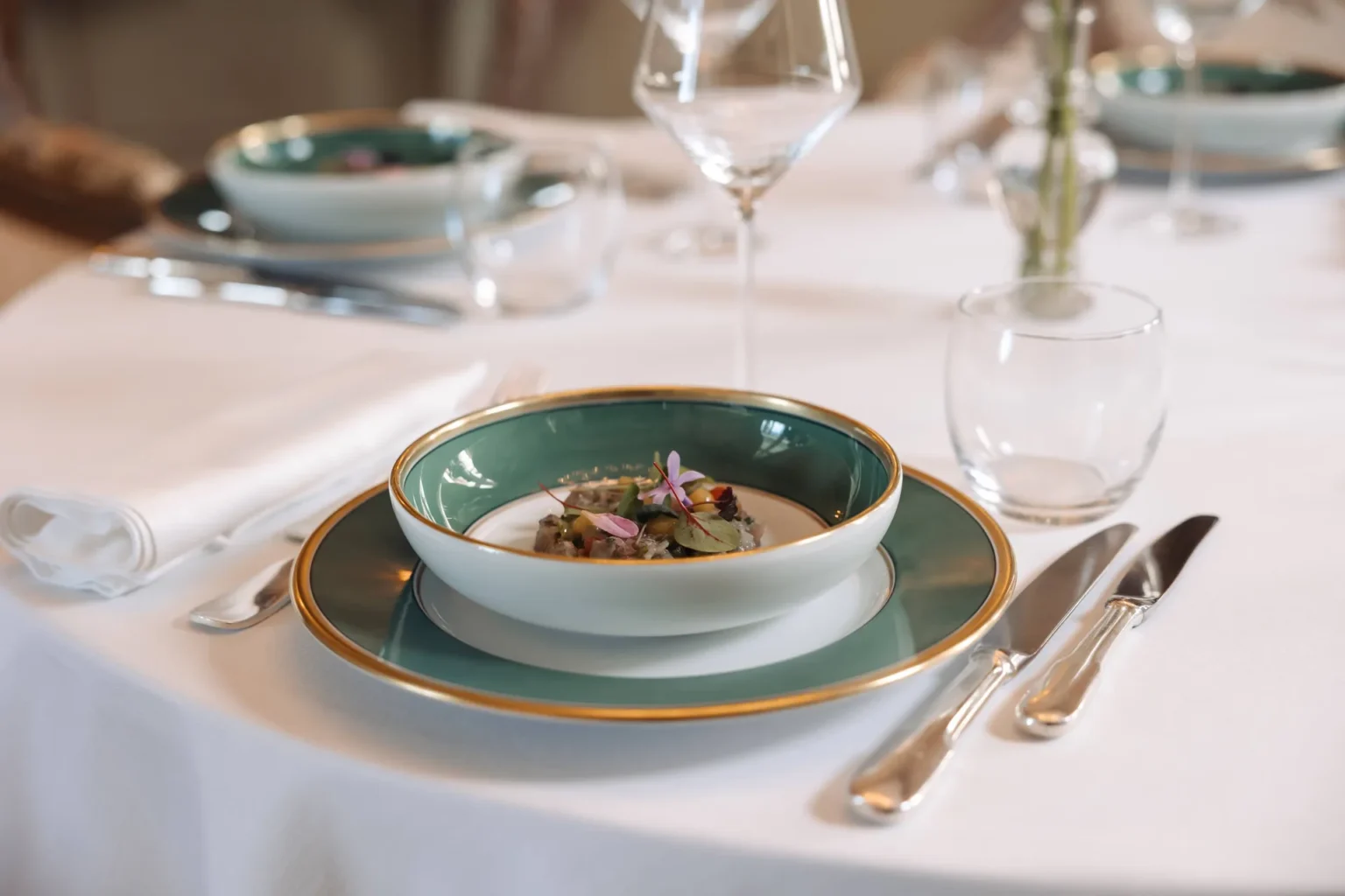A plated dish on a white tablecloth with glassware