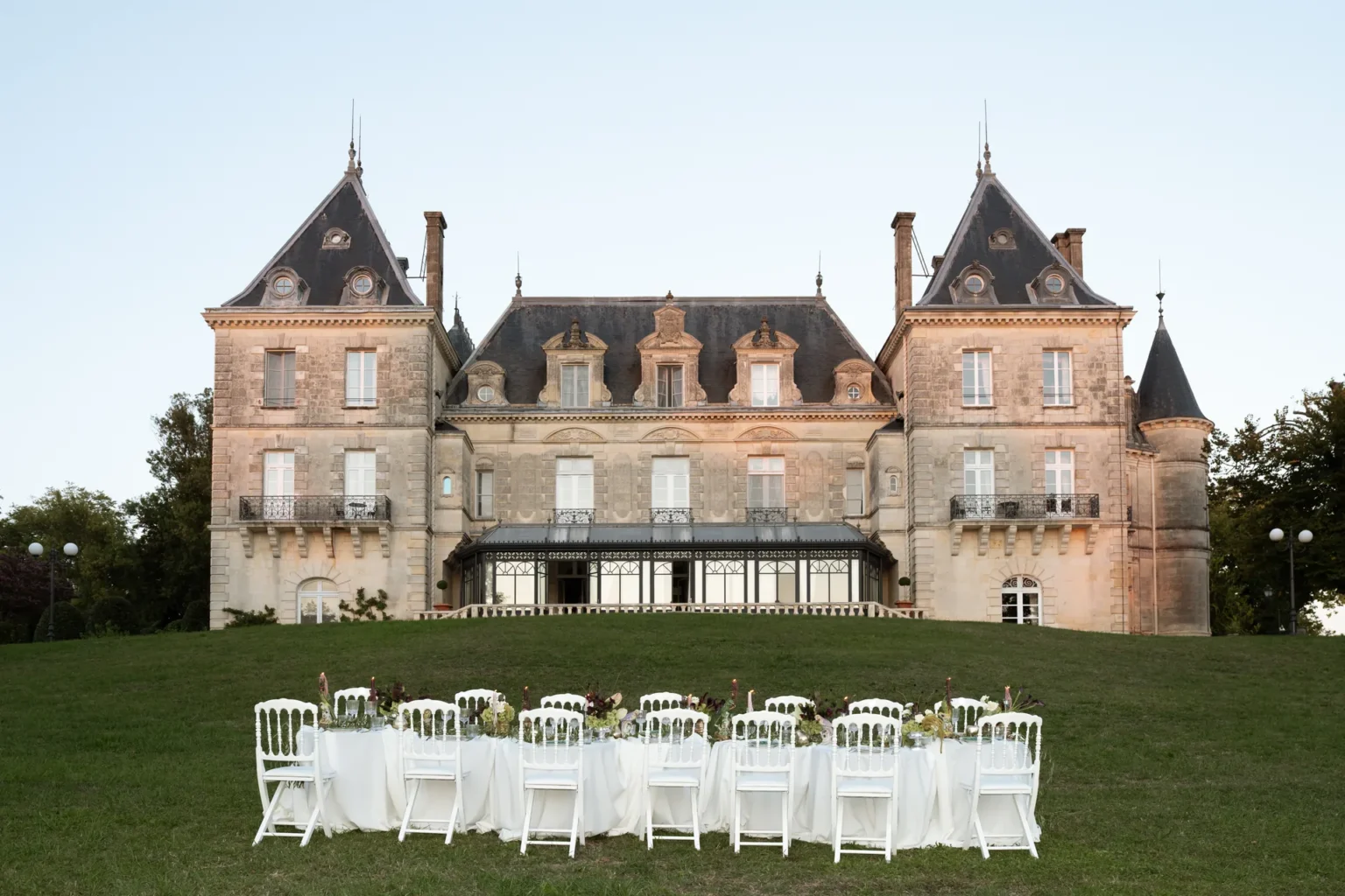 Chaises blanches disposées sur le pelouse en face de la façade du château