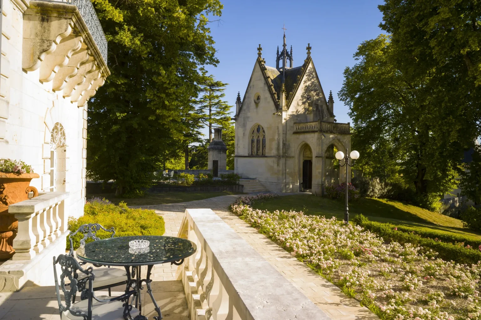 Une table de jardin sur la balustrade de la terrasse, donnant sur le pelouse et la chapelle du château
