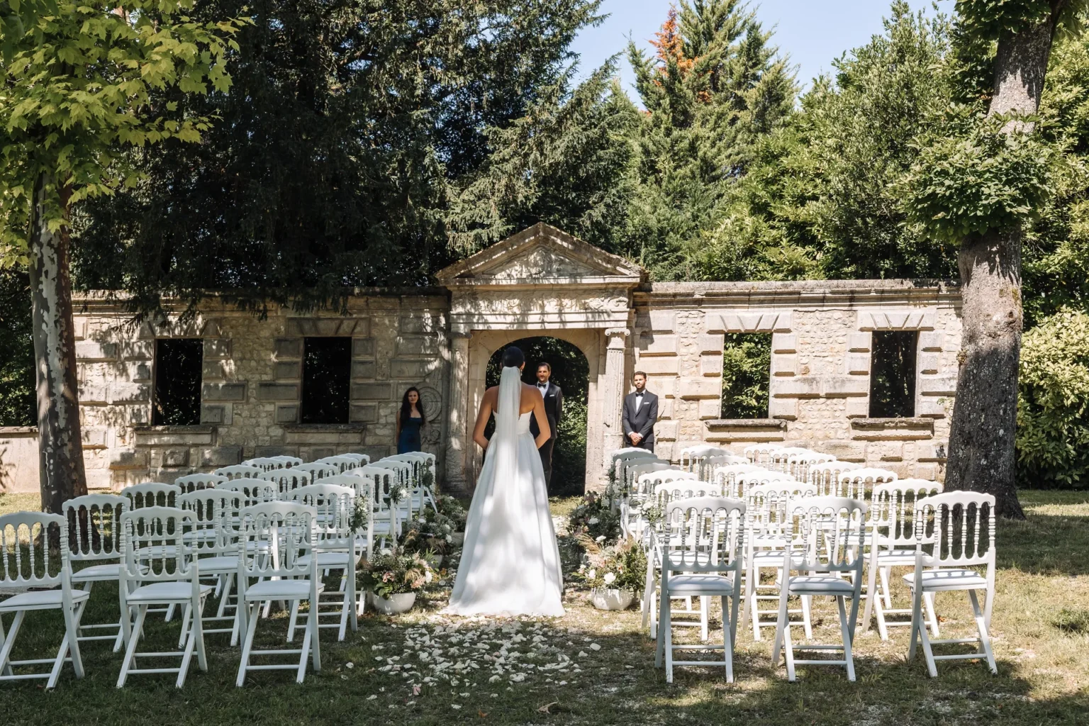 A wedding ceremony in the garden, the bride standing before rows of white chairs